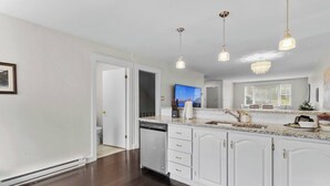 A modern kitchen with white cabinetry, a granite countertop, and pendant lighting. - Quidi Vidi King 3 Doubles Parking Office (St. John's)
