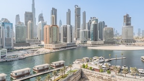 Paesaggio urbano con moderni grattacieli, una marina piena di barche e un’ampia spiaggia di sabbia.