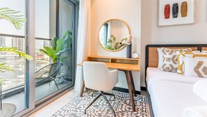 Una camera d'albergo moderna con un'ampia finestra, una scrivania, una sedia, un letto e uno specchio decorativo.