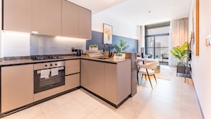 Una cucina moderna con elettrodomestici integrati, un'area pranzo con una sedia bianca e un'ampia finestra con vista sulla città.