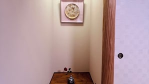 A narrow hallway with a wooden floor, a small table with a vase and a rose, and a framed artwork on the wall. - Camellia House, Tokyo, Zoshigaya, walkable to Ikebukuro station & Sunshine City (豊島区雑司が谷)