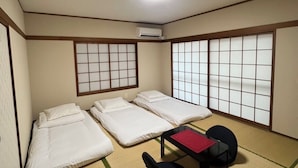 A traditional Japanese room with tatami flooring, four single beds, a small table with a red placemat, and sliding shoji doors. - Camellia House, Tokyo, Zoshigaya, walkable to Ikebukuro station & Sunshine City (豊島区雑司が谷)