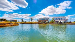 A waterfront property with two modern houses, a calm lake, and a clear sky. - Break Point Cottage | Canal-Front Stay w/ Pool Table Fun (Rockport)