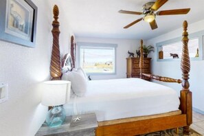 Une chambre à coucher avec un lit à baldaquin, un ventilateur de plafond, une table de chevet avec une lampe et une commode.