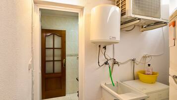 Un baño con un calentador blanco, un lavabo amarillo y una lavadora.