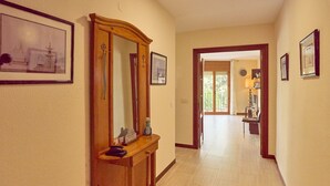 A hallway with a wooden console table, framed pictures on the walls, and a door leading to another room. - Apartment 'Luque Un Pueblo Con Encanto' with Balcony, Wi-Fi and Air Conditioning (Luque)