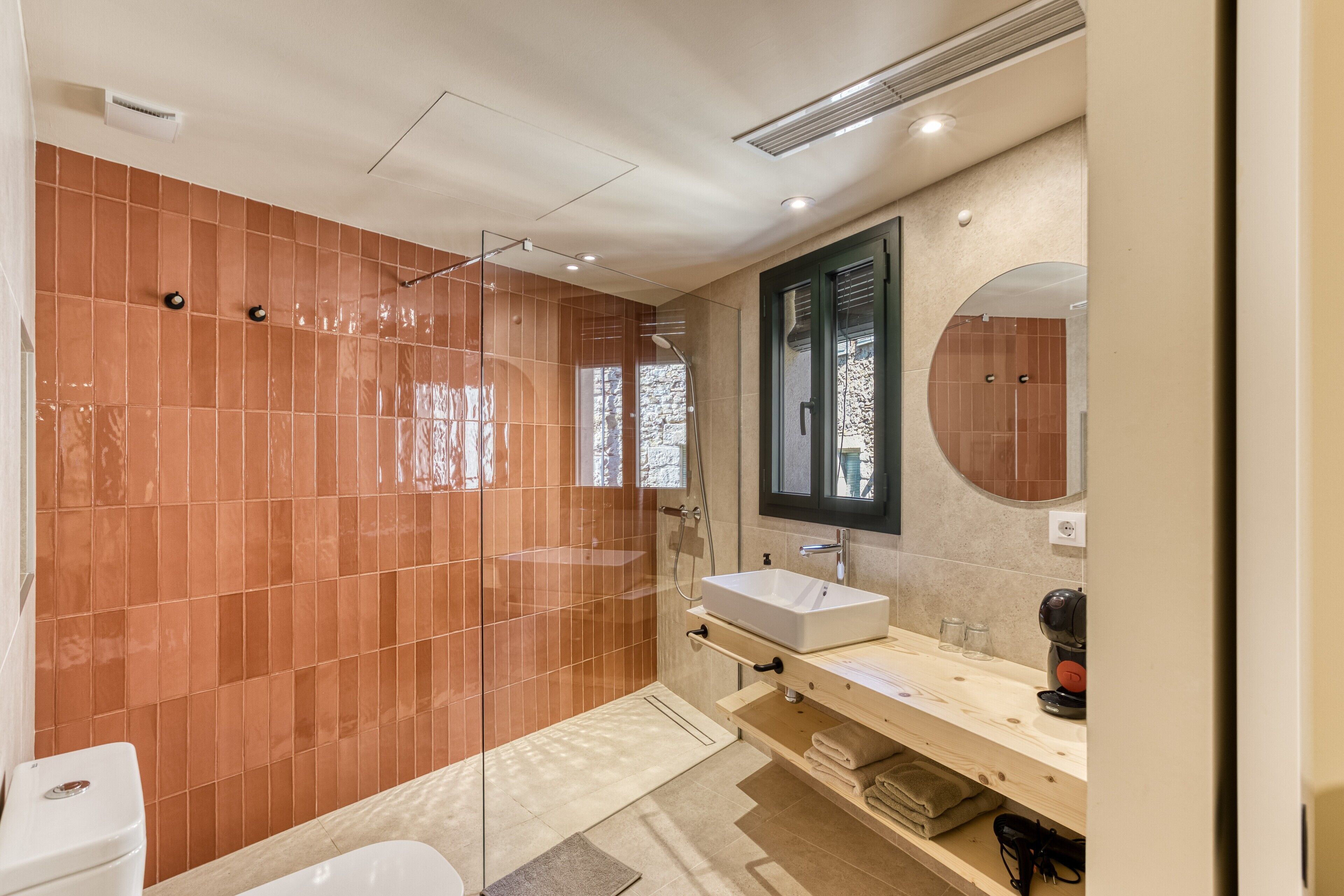 A modern bathroom with a glass-enclosed shower, a white sink, and a wooden vanity.