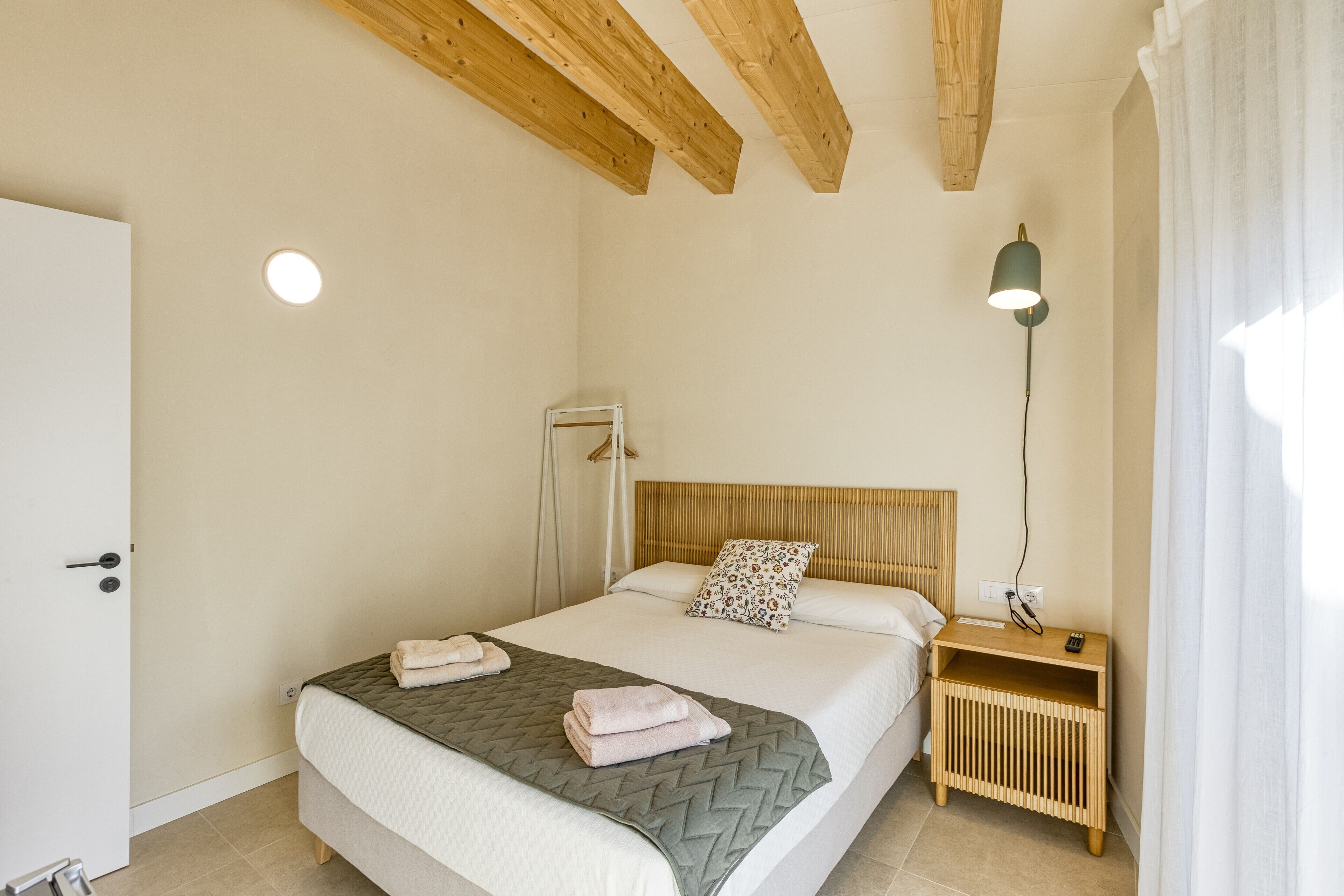 Une chambre à coucher avec un lit, une table de chevet, une lampe et une porte.