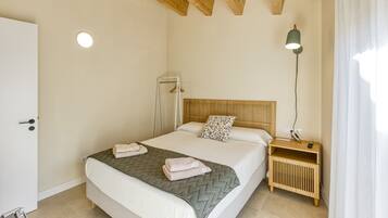 Une chambre à coucher avec un lit, une table de chevet, une lampe et une porte.