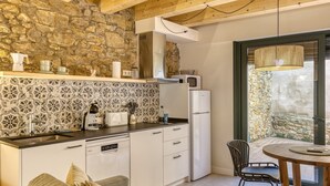 Een moderne keuken met een stenen muur, witte kasten en een eethoek met uitzicht op een stenen muur.