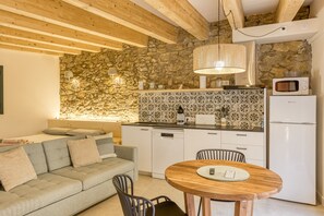 Eine gemütliche Küche mit Steinwand, Holzbalken, einem Esstisch und einer modernen Mikrowelle.
