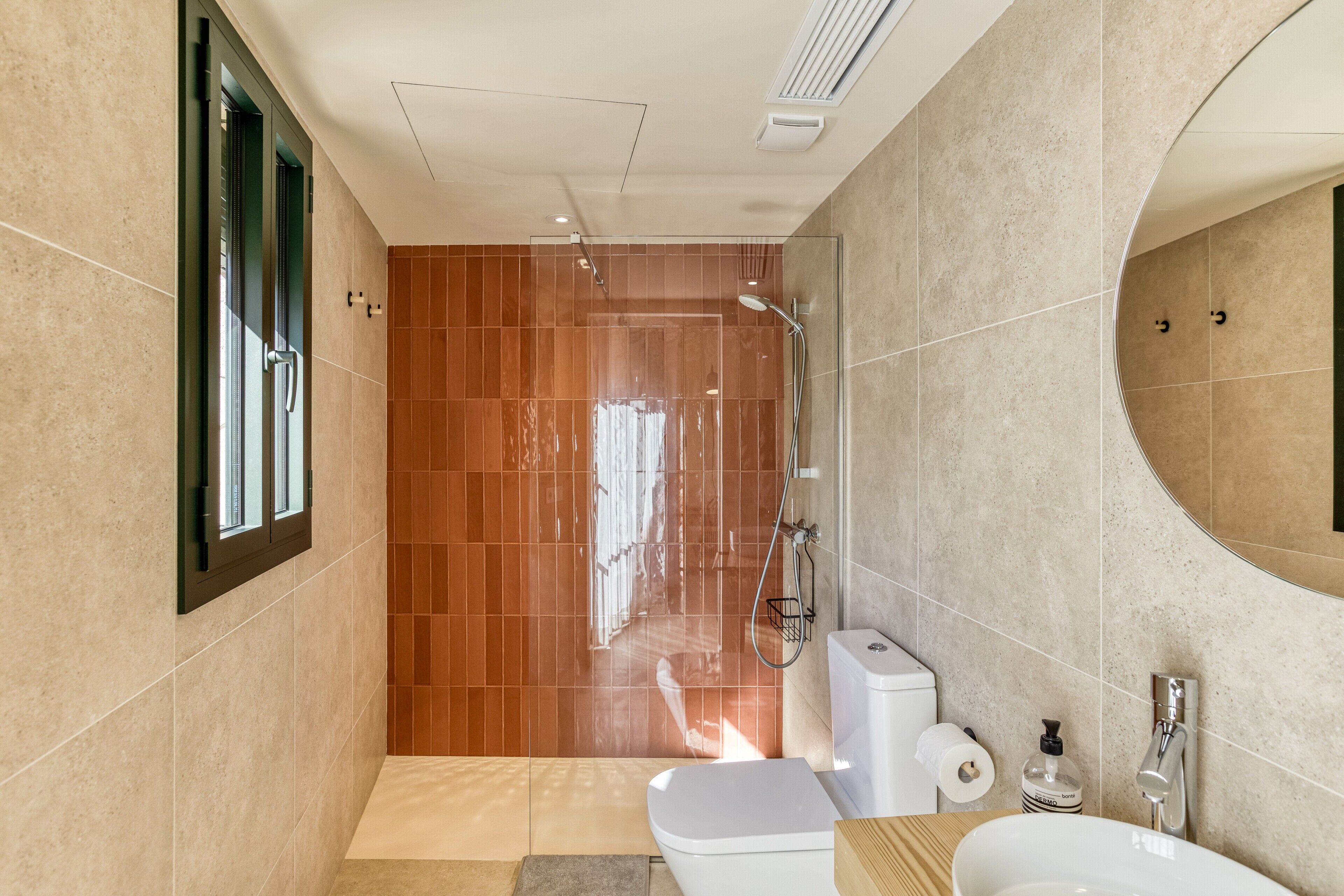 Een moderne badkamer met douche, toilet en wastafel.