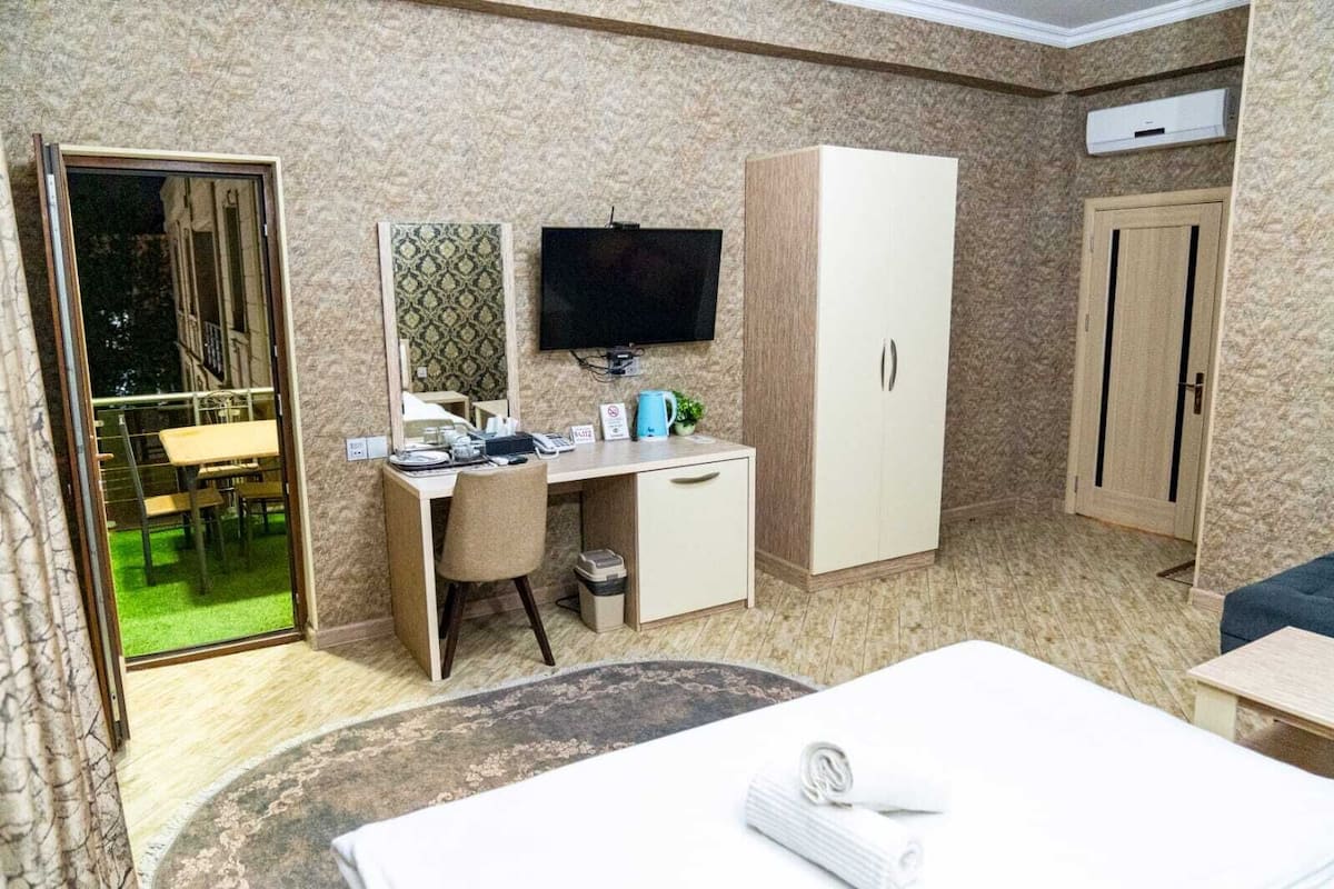 A hotel room with a desk, chair, wardrobe, television, and a bed.
