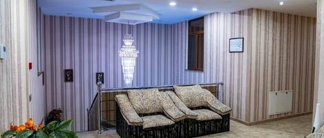 A modern hotel room with a sofa, striped wallpaper, a chandelier, and a staircase.