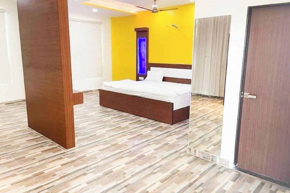 A bedroom with a bed, wooden floor, and a door.