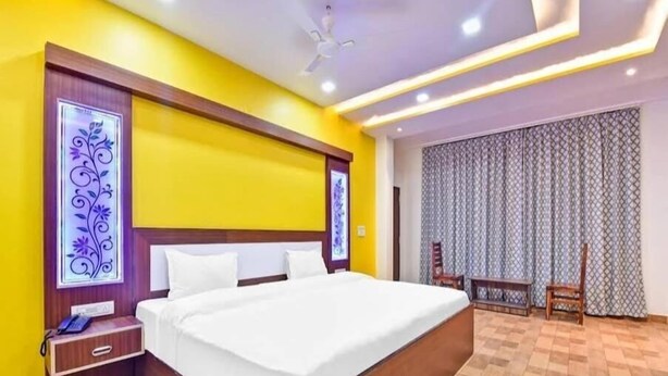Una habitación de hotel con una cama grande, cabecera de madera y una mesita de noche con teléfono.