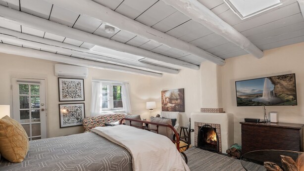 A bedroom with a bed, a fireplace, a TV, and a window. - New Listing! Charming Adobe Escape | Walk to Canyon Road & Galleries (Santa Fe)