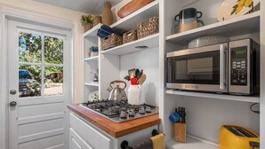 A compact kitchen with a gas stove, microwave, and a yellow toaster. - New Listing! Charming Adobe Escape | Walk to Canyon Road & Galleries (Santa Fe)
