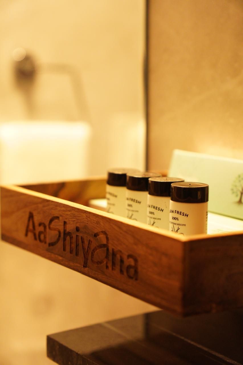 A wooden tray with jars labeled "Aashiyana" containing "100% Organic" products.