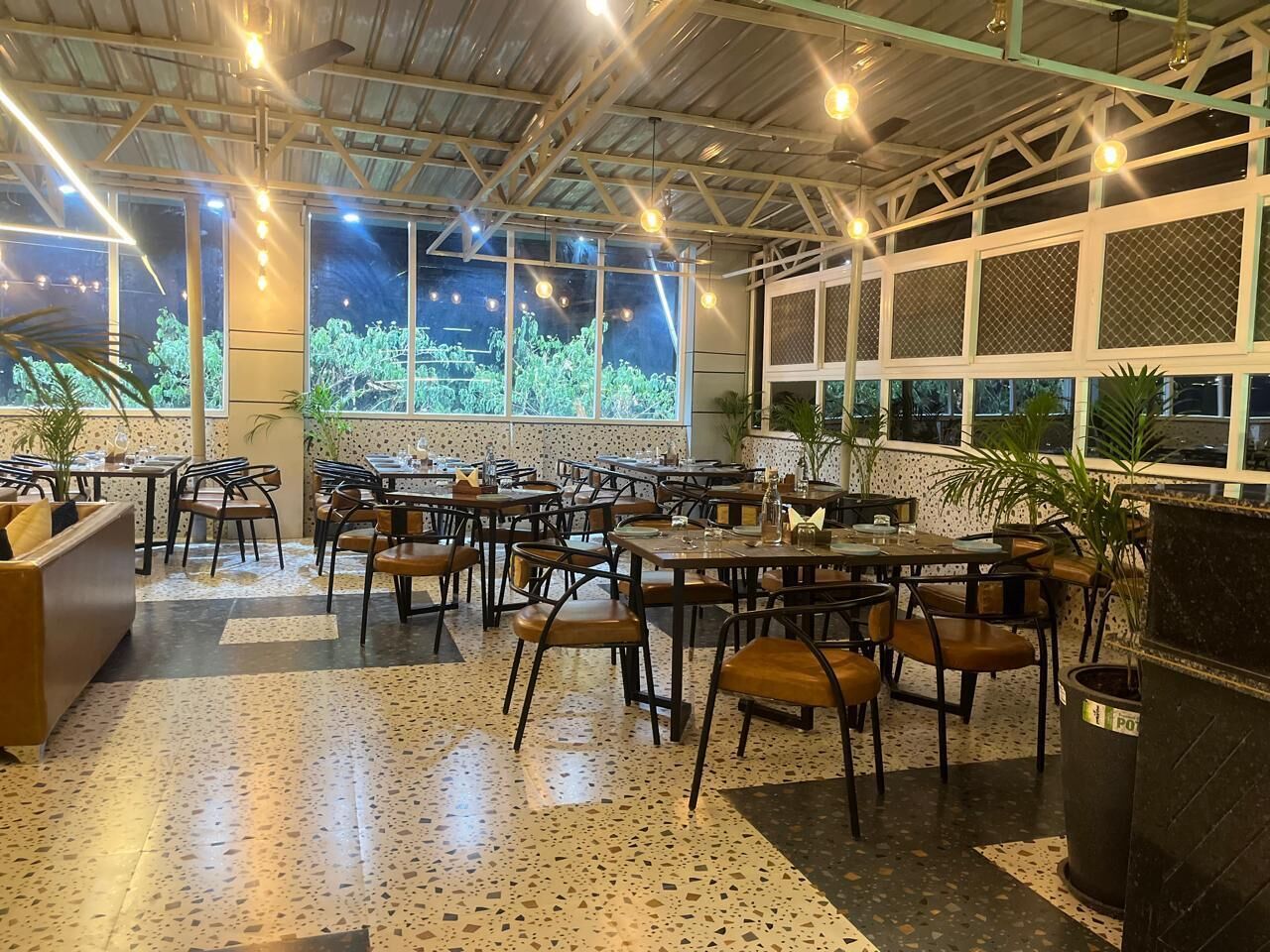 A restaurant with outdoor seating, large windows, and a ceiling with exposed beams.