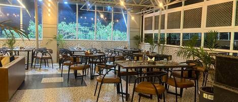 A restaurant with outdoor seating, large windows, and a ceiling with exposed beams.