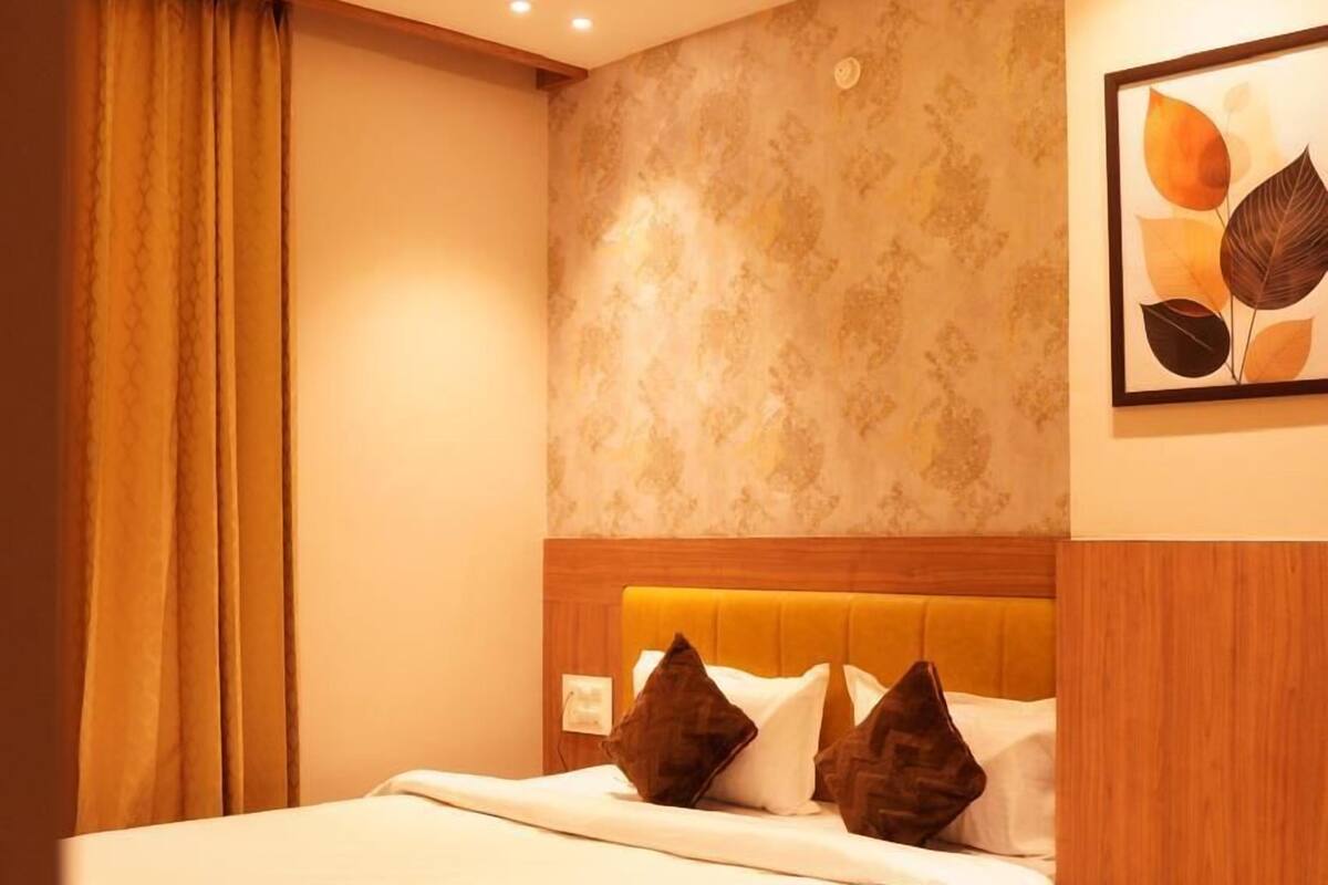 Una cama bien tendida con un cabecero de madera, un ventilador de techo y una pared con estampado floral.