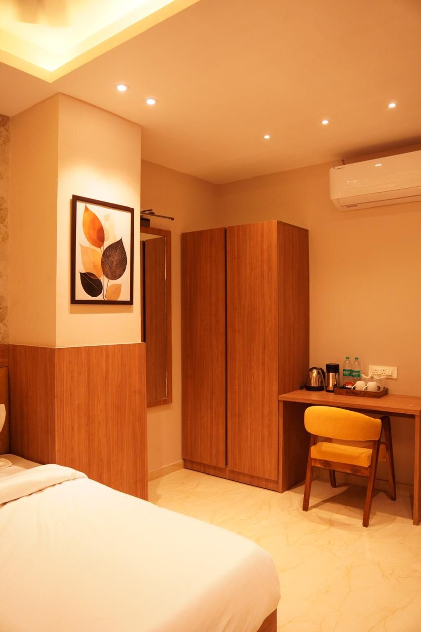 Une chambre d’hôtel comprenant un lit, un bureau avec une chaise, une armoire et une œuvre d’art encadrée accrochée au mur.