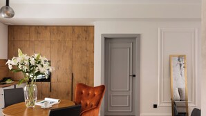 Un coin repas avec une table en bois, une chaise, un vase de fleurs et une porte en arrière-plan.