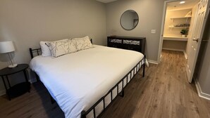 A bedroom with a bed, a nightstand, a dresser, a mirror, and a walk-in closet. - Central to Zoo and Baxter Arena, Pet Friendly (Omaha)