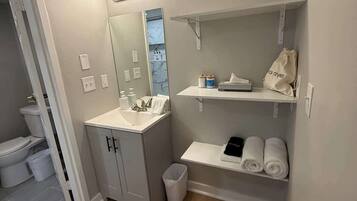 A modern bathroom with a sink, mirror, and shelves for toiletries.