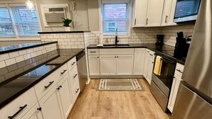 Una cocina moderna con armarios blancos, un refrigerador de acero inoxidable y piso de madera.