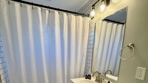 Un baño con bañera, lavamanos, inodoro y cortina de ducha.