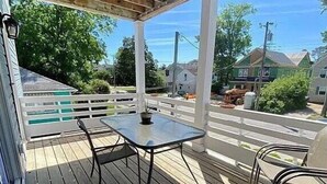 Eine überdachte Terrasse im Freien mit Tisch und Stühlen, mit Blick auf eine Wohngegend.
