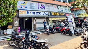 A multi-story building with signage for a hotel and various businesses, including a printing company. - Hotel Pleasure (Surat)