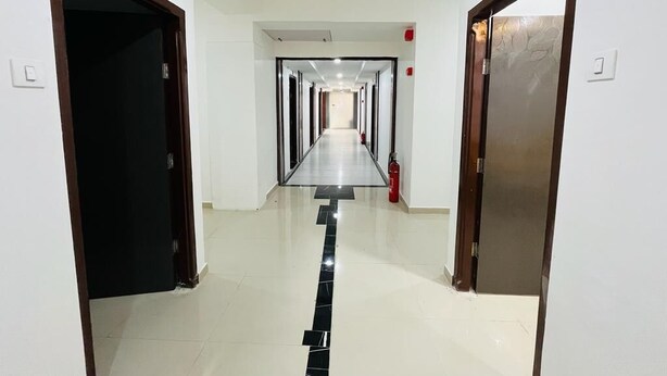 A hotel hallway with doors numbered 5 and 6, a fire extinguisher, and a tiled floor. - Hotel Pleasure (Surat)