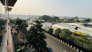 A cityscape with a busy street, buildings, and trees. - Hotel Pleasure (Surat)