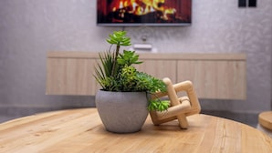 A round wooden table with a grey stone planter containing green plants and a wooden chair. - Serene Apartment (Kigali)