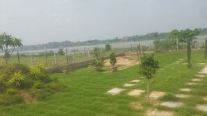 A grassy outdoor area with a small pool, potted plants, and a view of a body of water. - Mura Yoga Villa (Kasrawad)