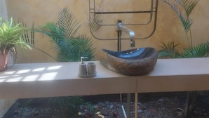A bathroom with a stone sink, a small mirror, and a potted plant. - Mura Yoga Villa (Kasrawad)