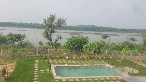 A swimming pool with a view of a river and greenery. - Mura Yoga Villa (Kasrawad)