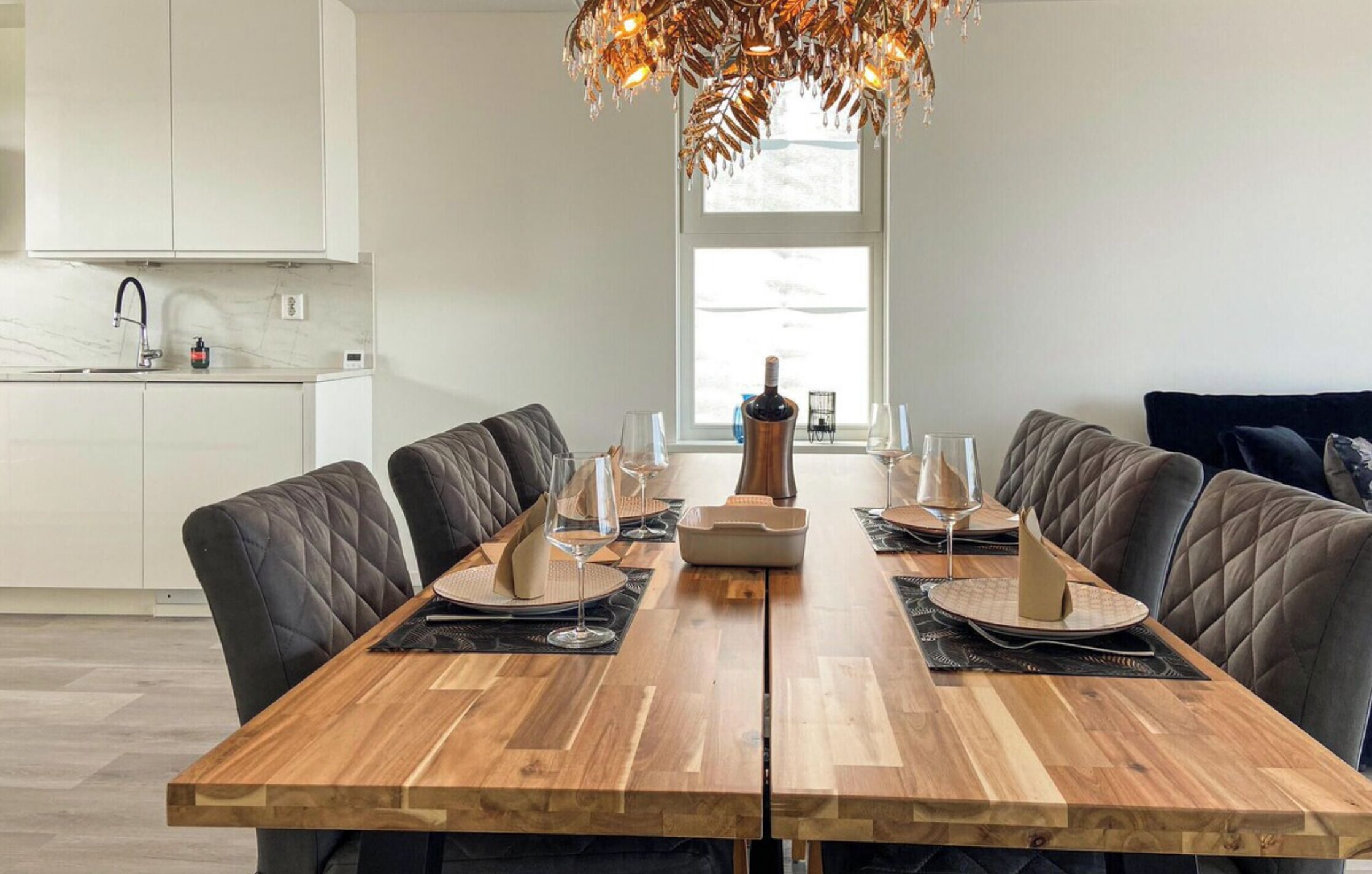 Un comedor moderno con una mesa de madera, sillas acolchadas negras y una lámpara decorativa.