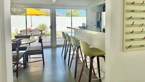 Una cocina moderna con barra, comedor y vistas al exterior.
