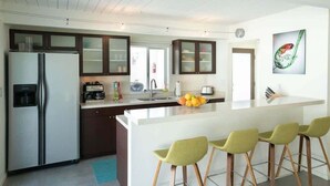 Una cocina moderna con una isla central, taburetes de bar y un refrigerador.