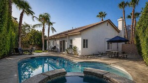 Une maison avec une piscine, du mobilier de jardin et des palmiers.