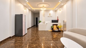 Ein Hotel-Empfangsbereich mit Marmorboden, einer Rezeption, einem Chandelier und einer Couch.