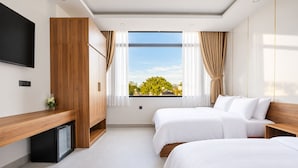 Ein Hotelzimmer mit zwei Betten, einem Fernseher, einer Minibar und einem Fenster mit Blick auf die Stadt.