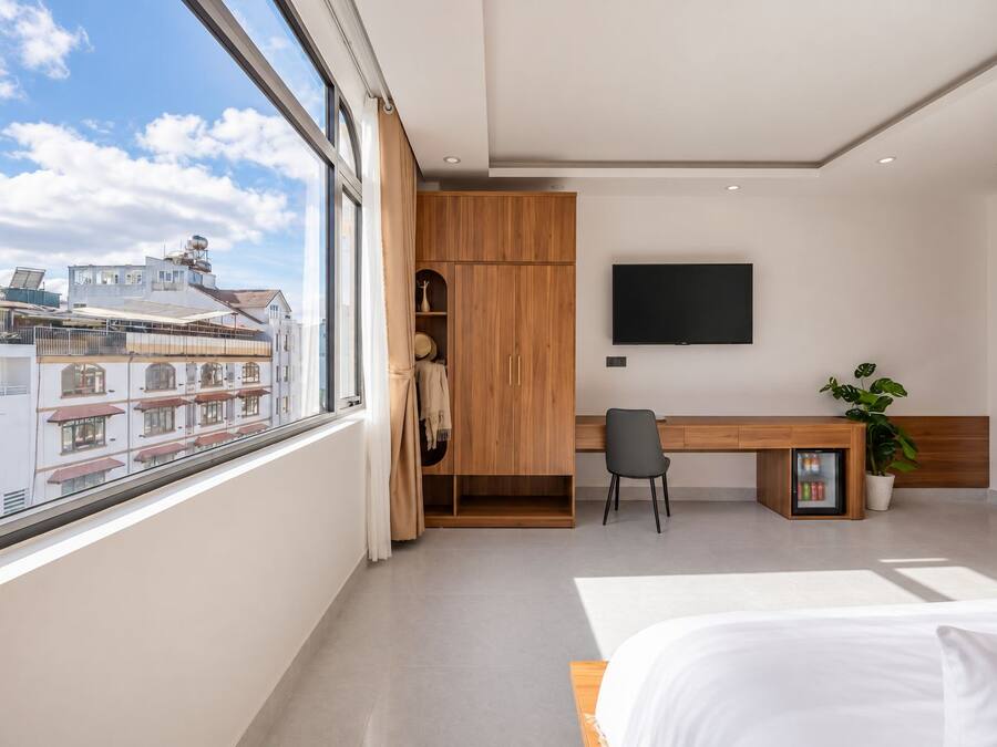 Un dormitorio moderno con un ventanal grande, una cama, un escritorio y un televisor.