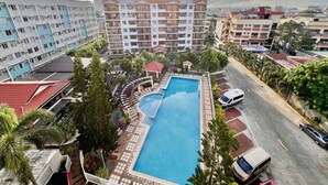 Ein Hotel mit mehreren Etagen, einem Schwimmbad und einem Parkplatz.