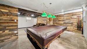 A room with a pool table, green hanging lamps, and wooden walls. - Peaceful Plum PA Home (Pittsburgh)