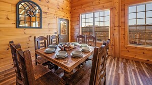 A wooden cabin dining room with a large table set for six, surrounded by wooden chairs. - Private Indoor Pool · Close 2 Dollywood · Mountain Views · Hot Tub + Game Room (Sevierville)